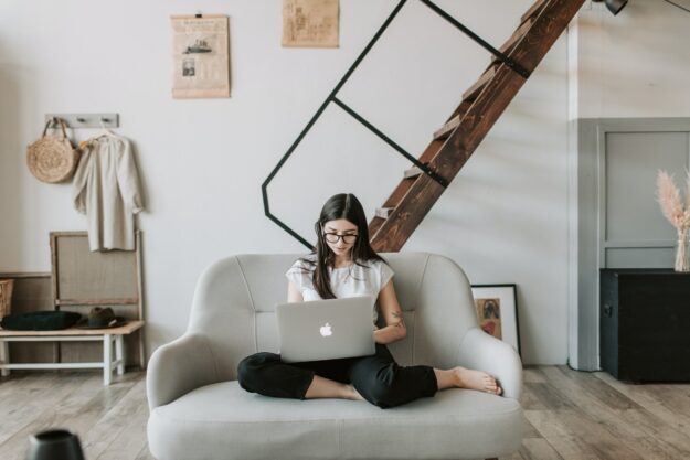 Frau mit Laptop und Kaffeetasse, arbeitet im Homeoffice, umgeben von Pflanzen, passend zum Thema WebshopTrends 2024.